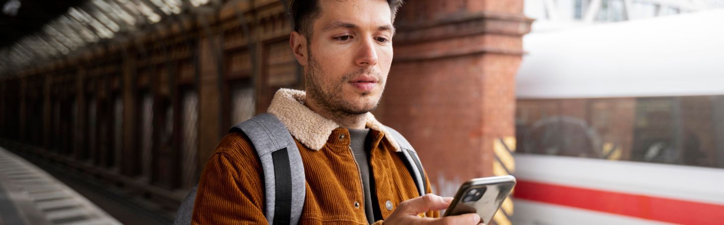 Mężczyzna z telefonem na dworcu kolejowym