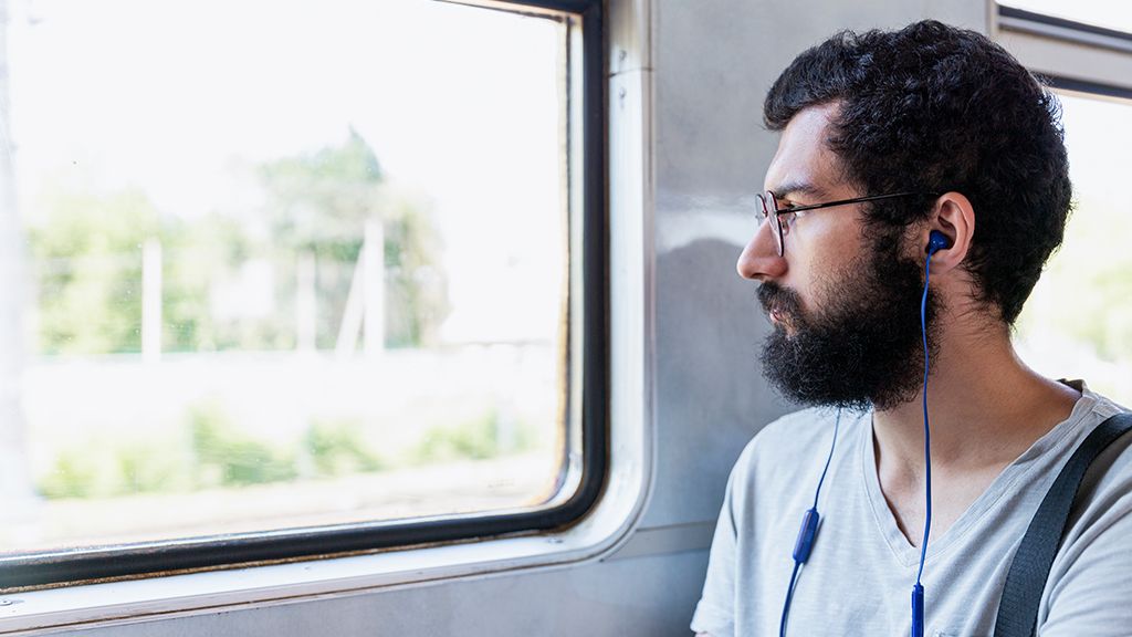 Młody człowiek w pociągu patrzący za okno - zniżki dla obcokrajowców w PKP