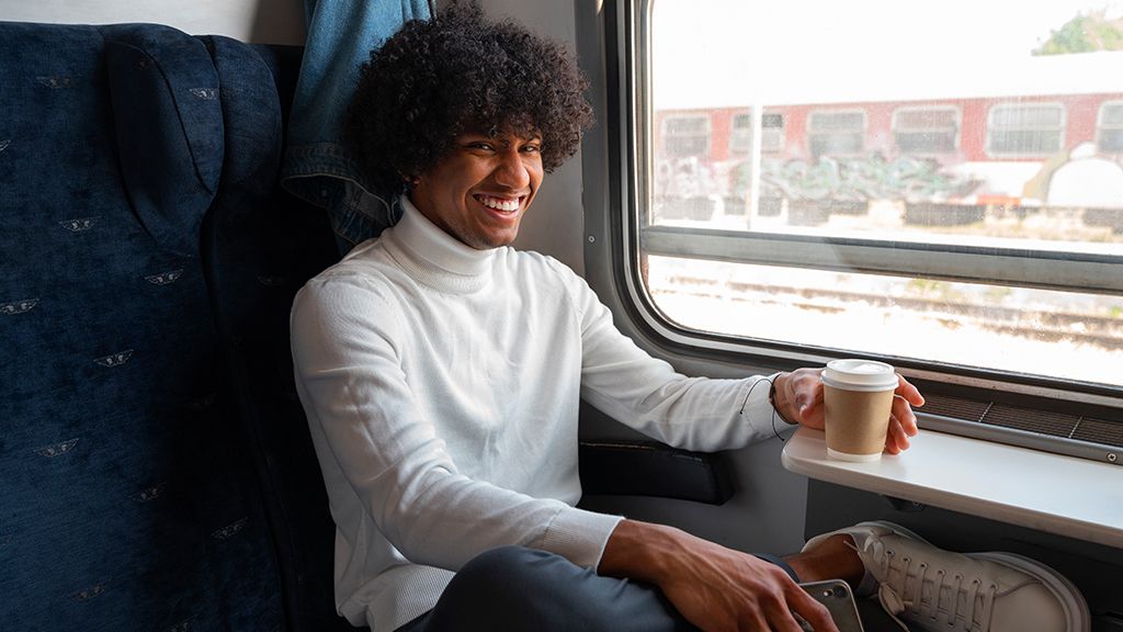Młody człowiek w pociągu z kawą