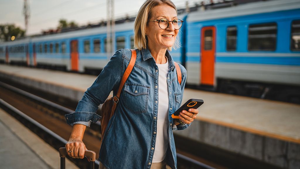 Kobieta czekająca na peronie z telefonem - Zniżki PKP dla nauczycieli