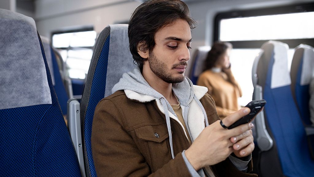 Młody człowiek z telefonem w pociągu