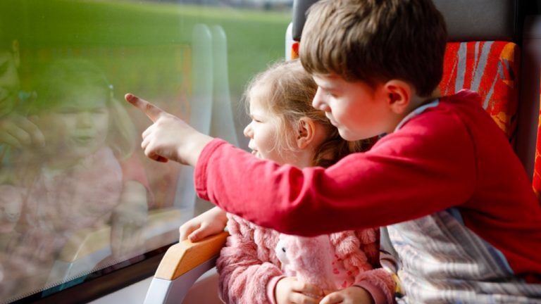 dzieci patrzące przez okno pociągu
