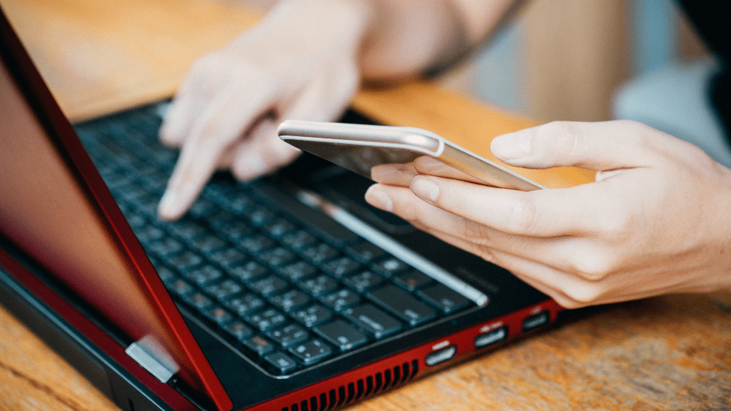 Osoba używająca laptopa i telefonu 