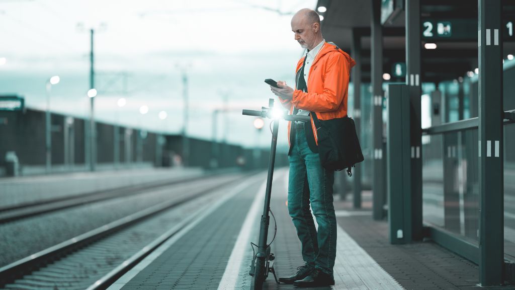 Mężczyzna z hulajnogą elektryczną na peronie