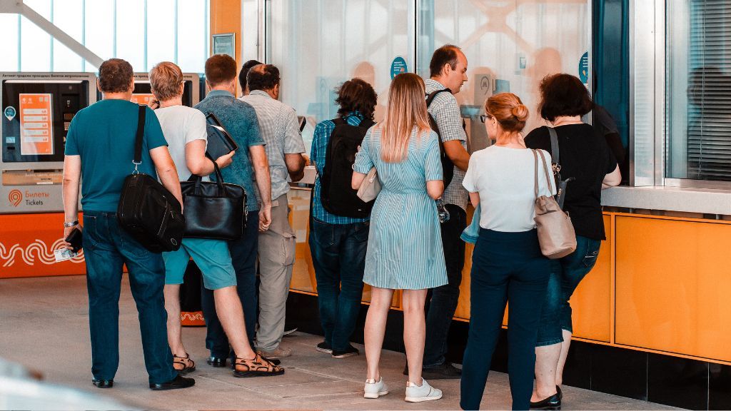 Ludzie stojący w kolejce do kasy biletowej